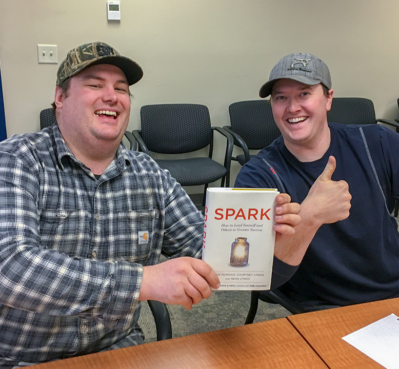 two men holding the SPARK book giving a thumbs up